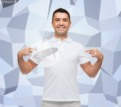Image of smiling man in t-shirt pointing fingers on himself
