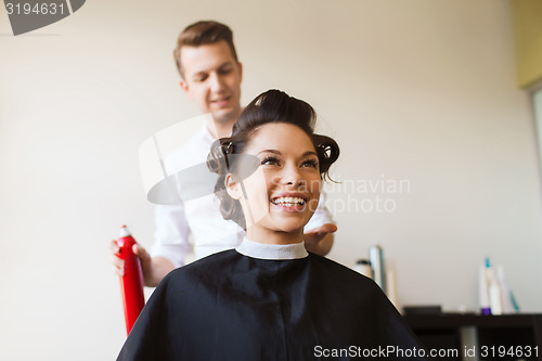 Image of happy woman with stylist making hairdo at salon