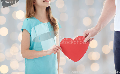 Image of close up of girl and male hand holding red heart