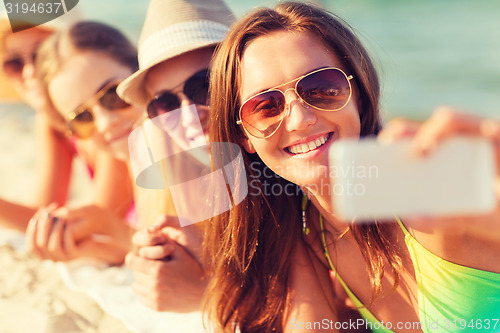 Image of close up of smiling women with smartphone on beach