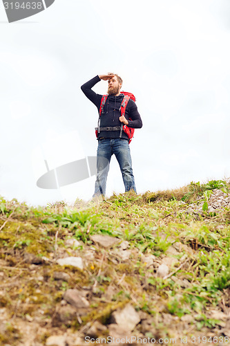 Image of tourist with beard and backpack looking far away