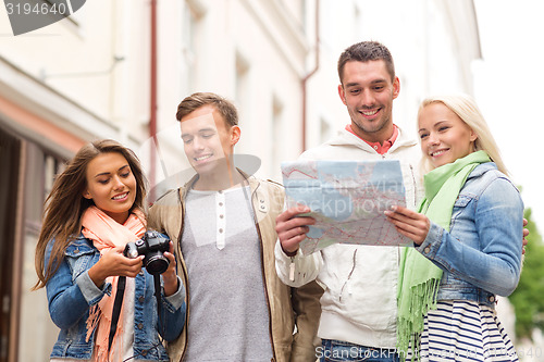 Image of group of smiling friends with map and photocamera