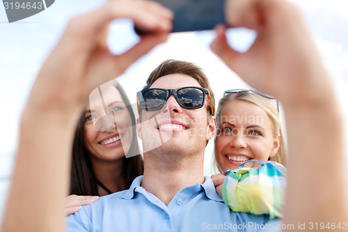 Image of group of friends taking selfie with cell phone