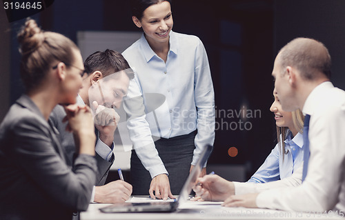 Image of smiling female boss talking to business team