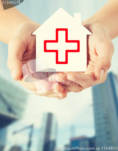 Image of hands holding paper house with red cross