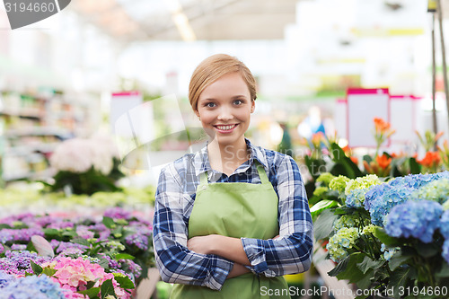 Image of happy woman with flowers in greenhouse