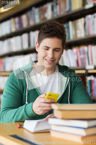 Image of male student with smartphone texting in library