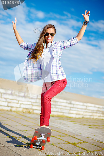 Image of smiling teenage girl riding skate outside