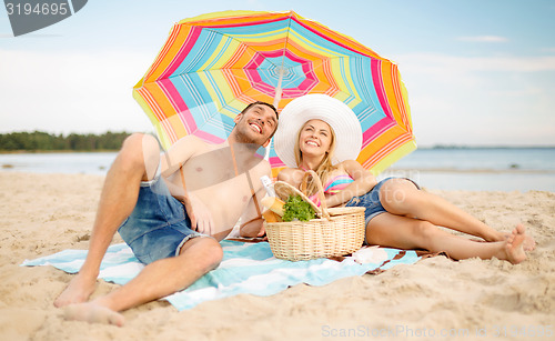 Image of couple having picnic and sunbathing on beach