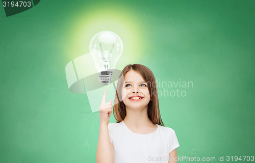 Image of smiling school girl pointing finger to light bulb