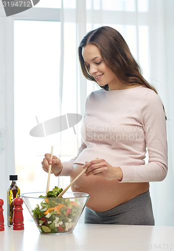 Image of happy pregnant woman preparing food at home