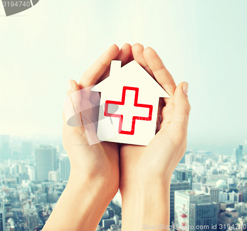 Image of hands holding paper house with red cross