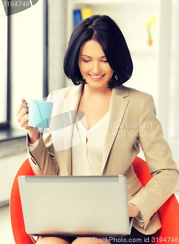 Image of businesswoman at home with laptop and cup