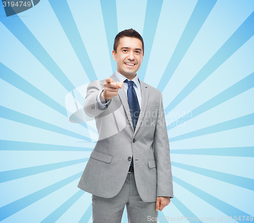 Image of happy smiling businessman in suit pointing at you