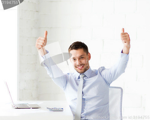 Image of happy businessman showing thumbs up in office