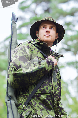 Image of young soldier or hunter with gun in forest