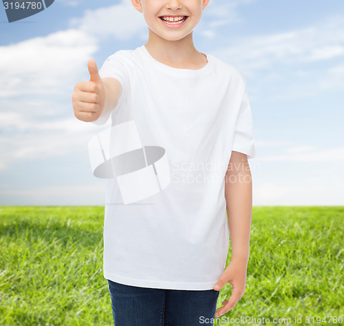 Image of close up of boy in white t-shirt showing thumbs 