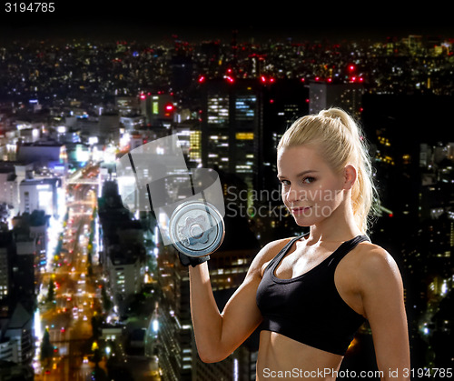 Image of young sporty woman with heavy steel dumbbell