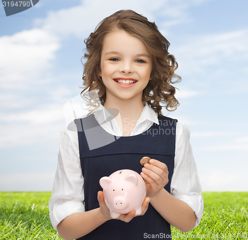 Image of happy girl holding piggy bank and coin