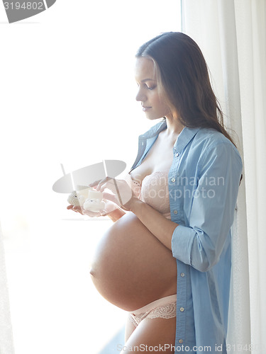 Image of happy pregnant woman with big bare tummy at home