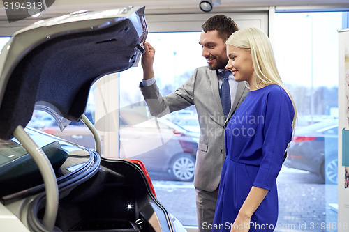 Image of happy couple with car dealer in auto show or salon