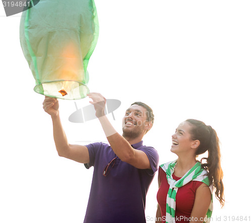 Image of happy couple with chinese sky lantern on beach