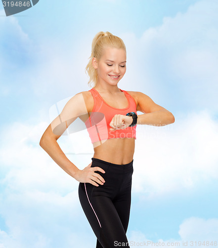 Image of smiling woman with heart rate monitor on hand