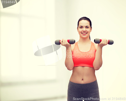 Image of young sporty woman with light dumbbells