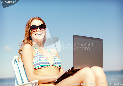 Image of girl looking at tablet pc on the beach