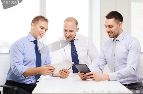Image of three smiling businessmen with tablet pc in office