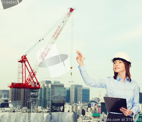 Image of smiling businesswoman in helmet with clipboard