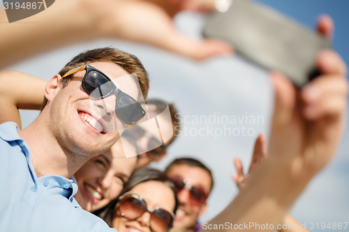 Image of group of friends taking selfie with cell phone