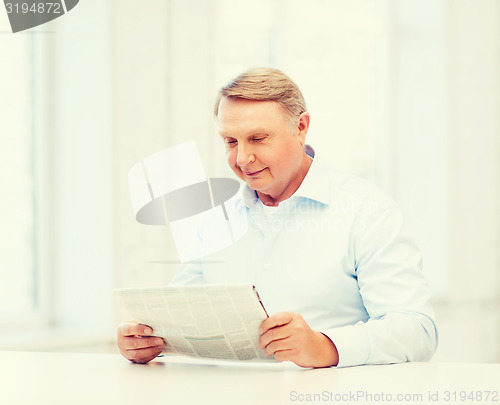 Image of old man at home reading newspaper