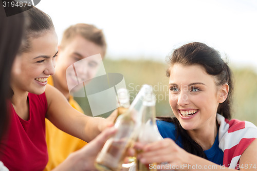 Image of happy friends with beer bottles on beach