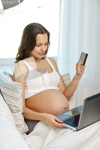Image of pregnant woman with laptop and credit card at home