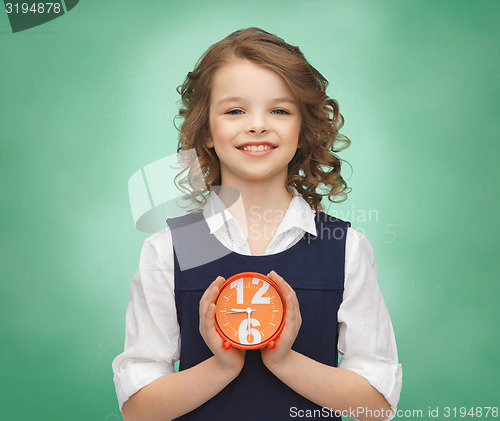 Image of happy girl with alarm clock over green background 