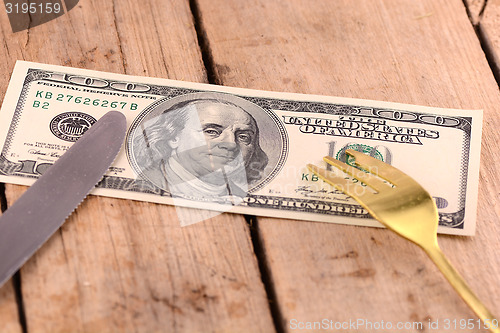 Image of american money on wooden plate with knife and fok