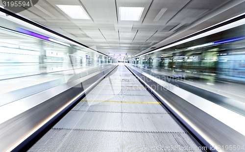 Image of symmetric moving blue escalator inside contemporary airport