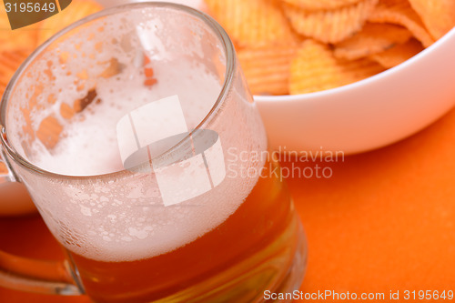 Image of Glass of light beer and potato chips on a wooden table
