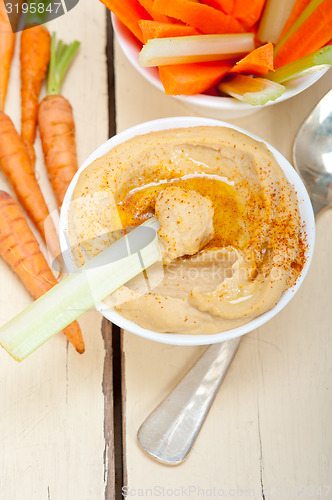 Image of fresh hummus dip with raw carrot and celery 