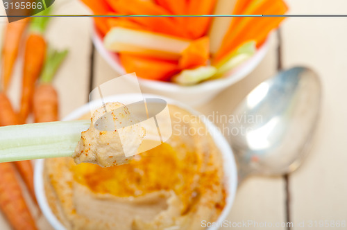 Image of fresh hummus dip with raw carrot and celery 