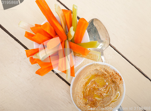 Image of fresh hummus dip with raw carrot and celery 