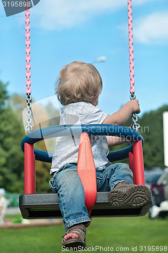 Image of Cute baby boy watching back on swing