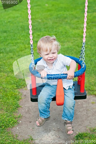 Image of Cute baby boy playing on swing 