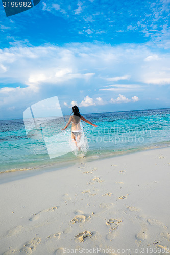 Image of Girl walking along a tropical beach in the Maldives.