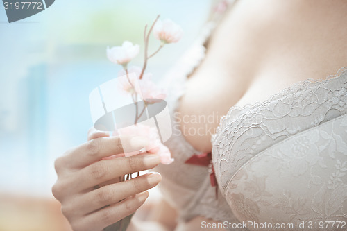 Image of Woman in brassiere holding Sakura flower