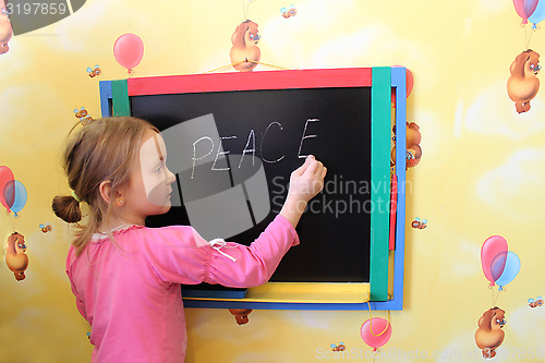 Image of The girl writes on a blackboard a word the peace