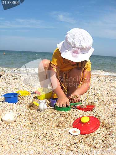 Image of The little girl plays at the sea