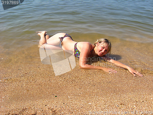 Image of girl laying on sand at the seacoast