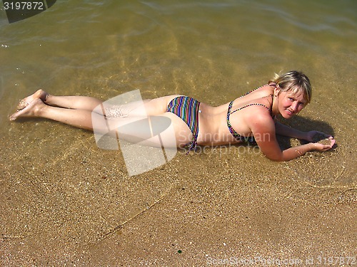 Image of The girl laying on sand at the seacoast